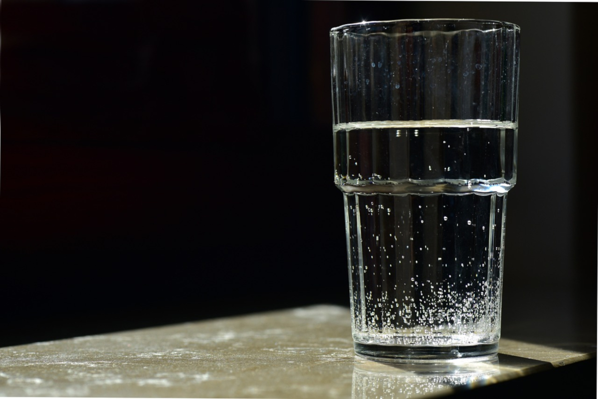 Zdjęcie przedstawia stojącą szklankę wypełnioną wodą. 