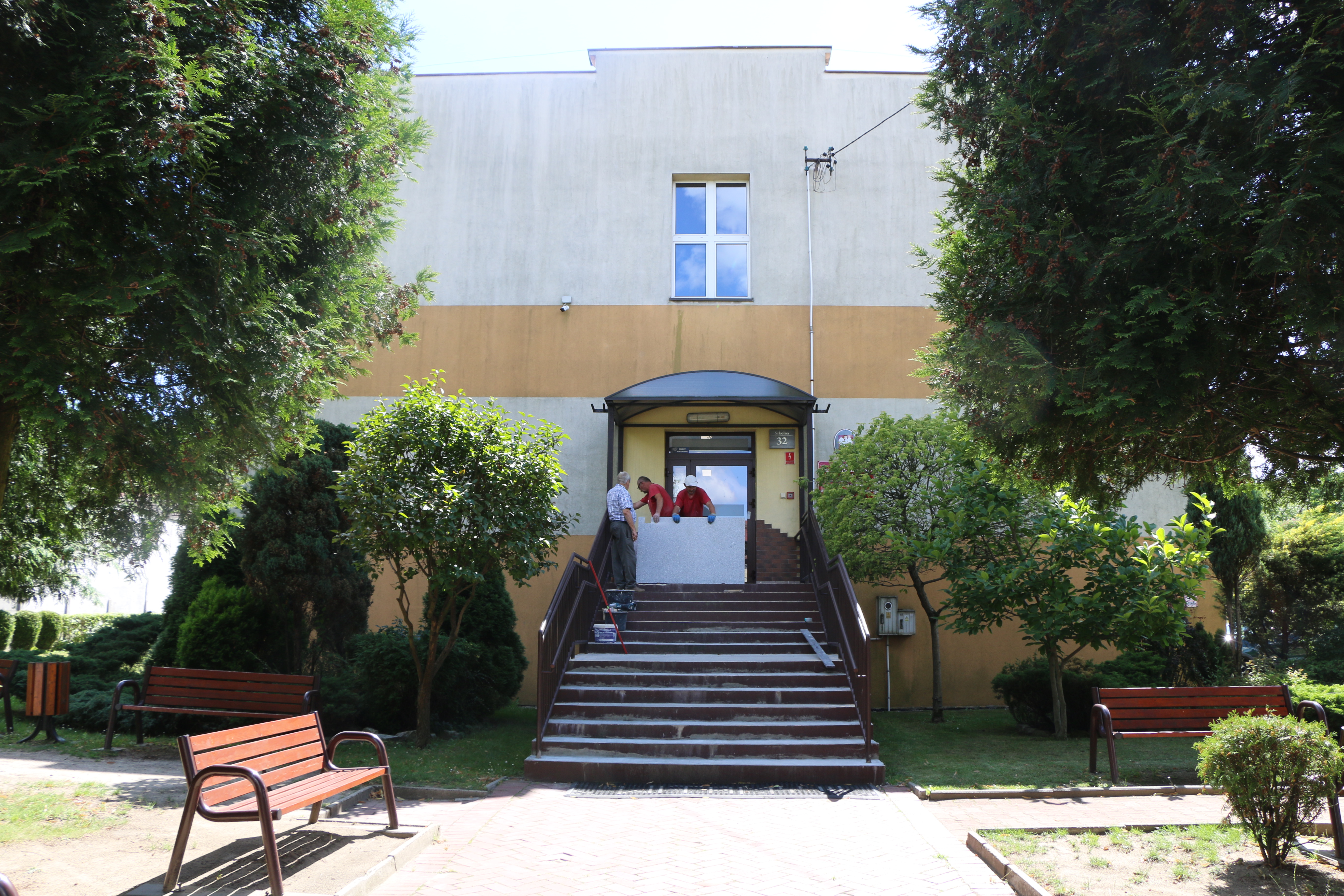 Na zdjęciu widać budynek szkoły w Psarach. Ekipa remontowa wykonuje prace związane z przygotowaniem schodow do ich rozebrania i położenia nowego materiału - granitu.